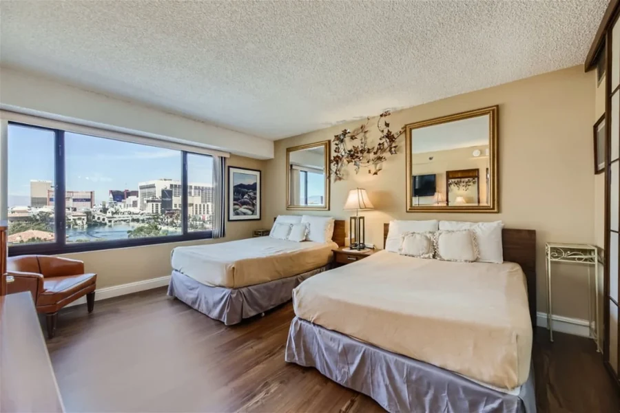 Bedroom with two beds, large windows and wall mirrors